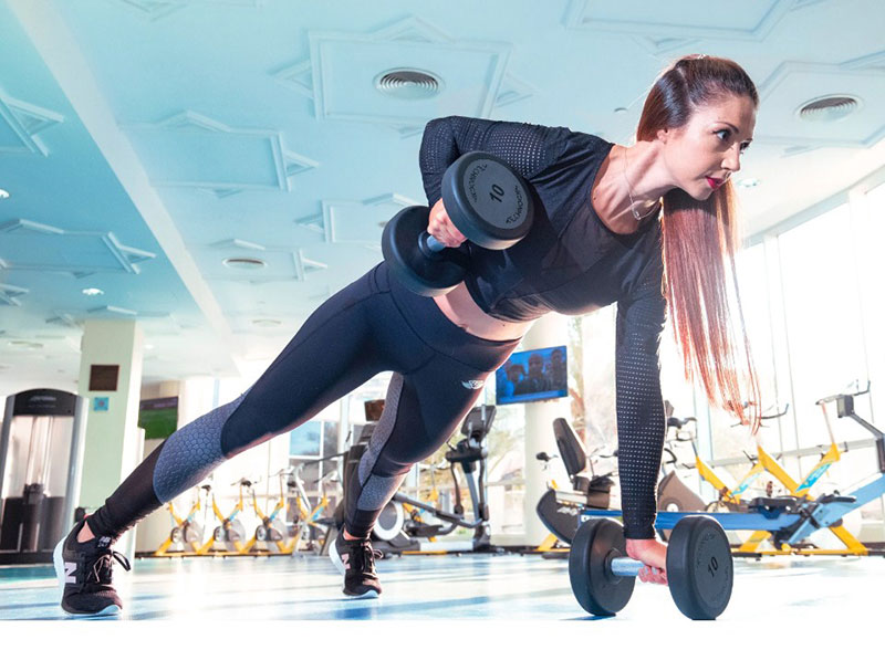 a woman training with dumbbells in a gym